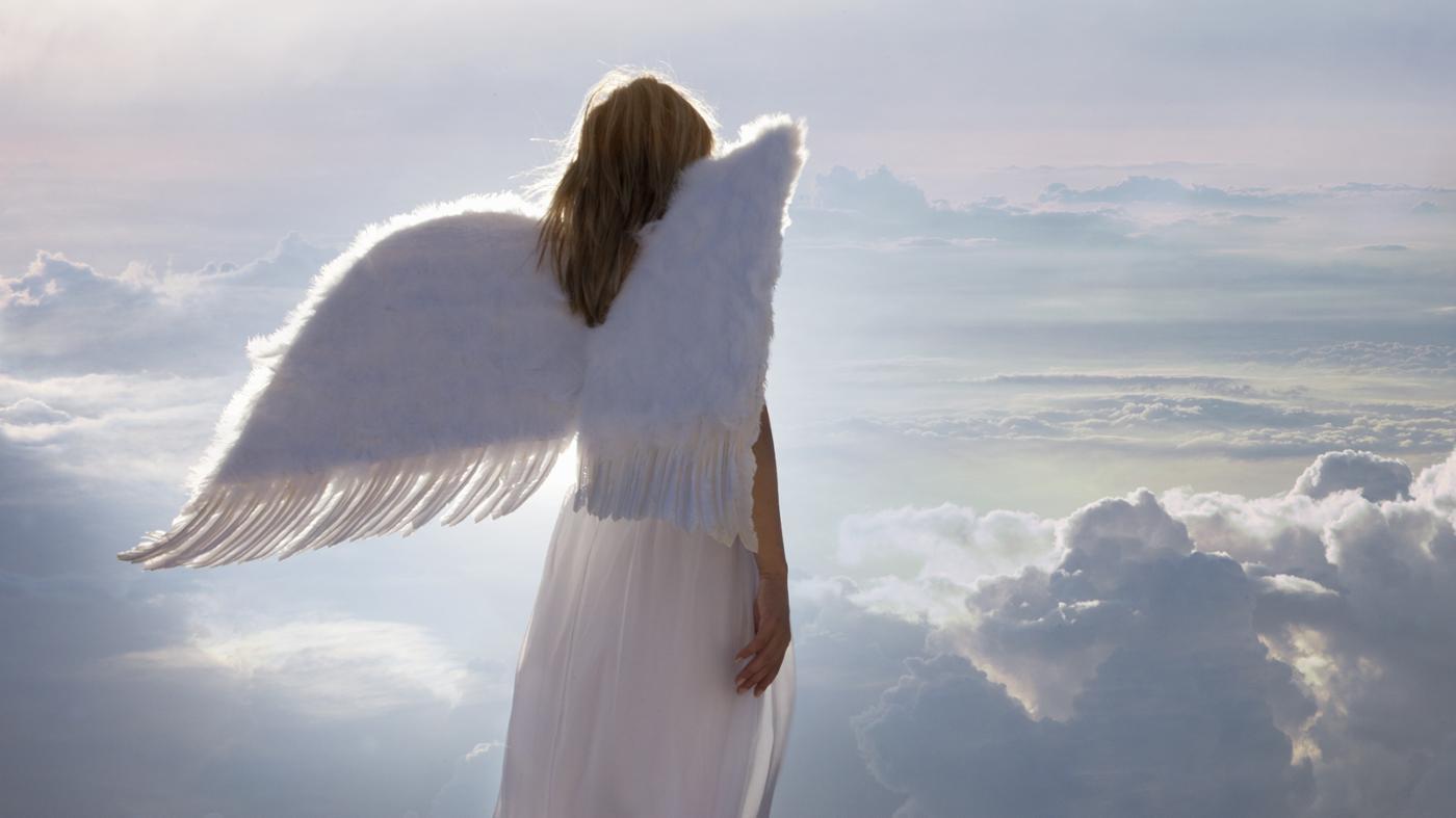angel or archangel with wings watching from clouds